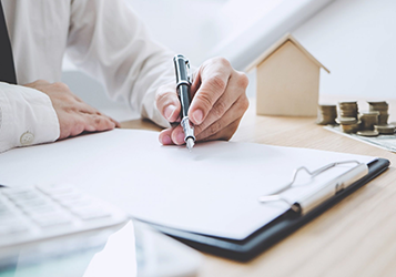 A person writing on paper with a pen.