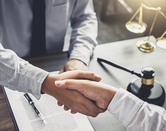 A man and woman shaking hands over papers.