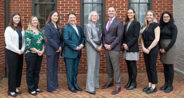 Nine professionally dressed people standing outdoors